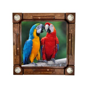 May include: Wooden framed game board featuring a vibrant image of two parrots. The parrots are a blue and yellow macaw and a red macaw. The frame is a dark brown color with metal accents. The game board is square.