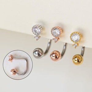Pu&ograve; includere: Tre orecchini a bilanciere curvi in argento, oro rosa e oro. Ogni orecchino presenta una piccola gemma rotonda e trasparente nella parte superiore, con una gemma pi&ugrave; piccola sottostante. La parte inferiore di ogni orecchino ha una sfera di metallo abbinata.