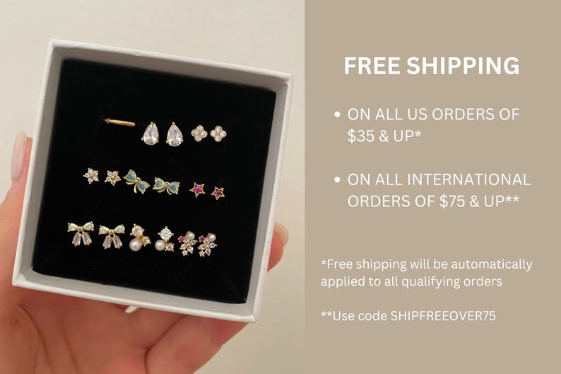 May include: A collection of gold-toned earrings displayed in a black box. The earrings include studs with various designs: teardrops, flowers, stars, bows, and pearls. The image also includes the text "FREE SHIPPING".
