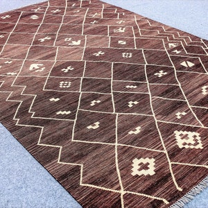May include: A brown and white geometric patterned rug with a fringe border. The rug has a traditional Moroccan design.