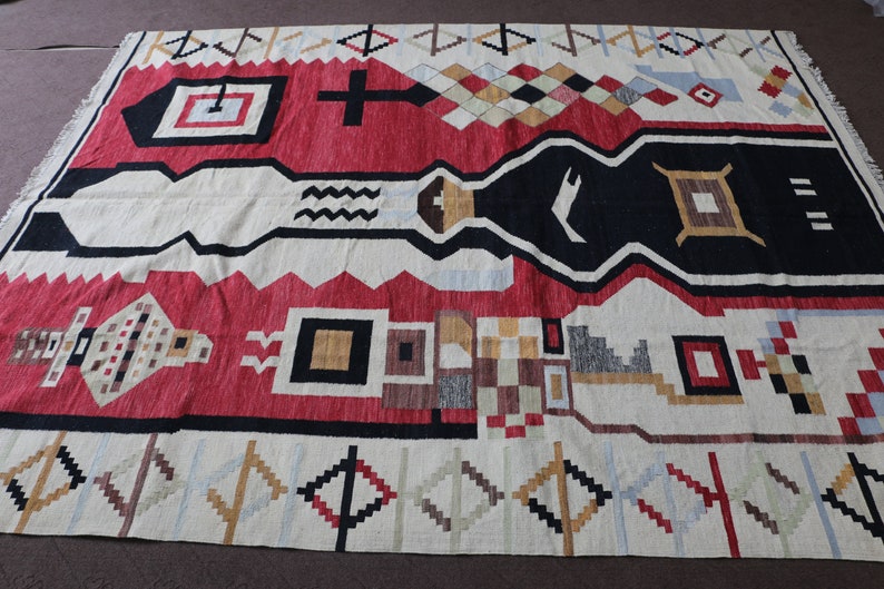 Puede incluir: Una alfombra geom&eacute;trica colorida con un patr&oacute;n rojo, negro, blanco y beige. La alfombra tiene un dise&ntilde;o tradicional con detalles intrincados.