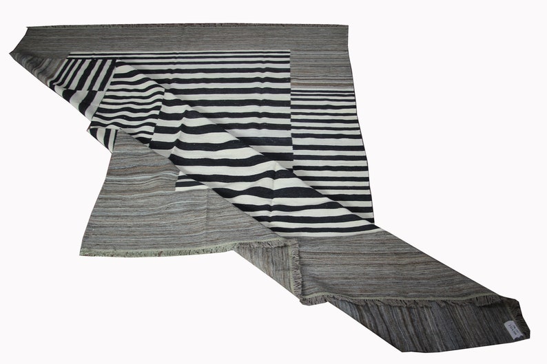 May include: A black and white striped rug with a gray border. The rug is folded in half and the stripes are visible on both sides.