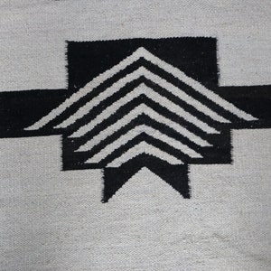 May include: Black and white geometric pattern woven into a rug. The pattern features a series of overlapping triangles.