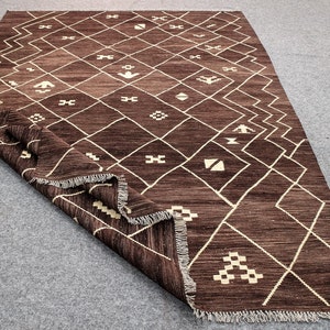 May include: A brown and cream patterned rug with a geometric design. The rug has a fringe border.