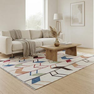 May include: A rectangular area rug featuring a cream-colored base with a repeating geometric pattern of chevron-like arrows in shades of blue, red, green, brown, and black. The rug has a low-pile texture and short fringe along the shorter edges.