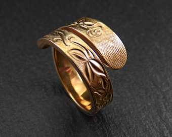 May include: A gold-toned ring with a floral design. The ring is made of two bands that are intertwined.
