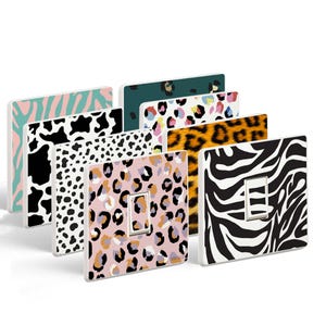 Peut inclure: Ensemble de huit caches-prises avec différents motifs d'imprimés animaliers, notamment des motifs zèbre, léopard, vache et guépard. Les caches-prises sont blancs avec une finition brillante.