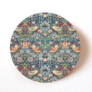 Può includere: Sottobicchiere rotondo con un motivo floreale e di uccelli dettagliato. Il design presenta uccelli, fiori e bacche nelle tonalità del blu, verde, rosa e giallo. Il sottobicchiere ha un bordo in legno e uno sfondo bianco.