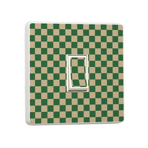 Peut inclure: Un interrupteur mural blanc avec un motif à carreaux verts et beiges. L'interrupteur lui-même est blanc. Le couvercle est carré et a des bords arrondis.