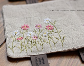 May include: Close-up of a beige linen coaster with embroidered pink and white daisies. The coaster has a stitched border and a brown tag that reads "JUYA'S Hand Made". The text "©2017. JuYaLove Design. All right reserved." is also visible.