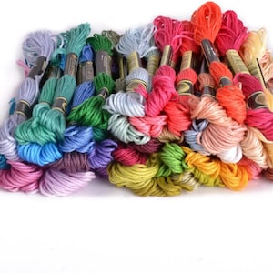 May include: A collection of colorful embroidery floss spools in various shades of blue, green, red, pink, yellow, and orange. The spools are arranged in a semi-circle, with the ends of the floss spilling out.