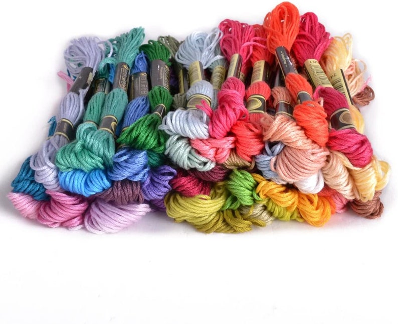 May include: A collection of colorful embroidery floss spools in various shades of blue, green, red, pink, yellow, and brown. The spools are arranged in a semi-circle, with the ends of the floss spilling out.