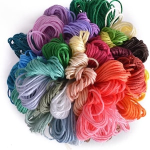 May include: A collection of colorful embroidery floss spools in various shades of green, blue, purple, pink, red, orange, yellow, brown, and white.