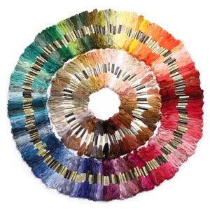 May include: A large collection of embroidery floss spools arranged in a circle, with colors ranging from green to purple. The spools are organized by color, creating a rainbow effect.