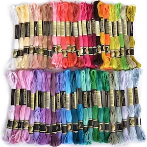 May include: A collection of 50 embroidery floss spools in a variety of colors, including pink, purple, blue, green, yellow, orange, red, and brown. Each spool is labeled with the brand name "Anchor" and a number.