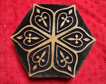 Puede incluir: Un sello de impresión de madera con un diseño geométrico negro y marrón. El diseño presenta una estrella de seis puntas con detalles intrincados.