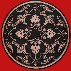 May include: A round, wooden decorative piece with an intricate, symmetrical design. The design features a dark, possibly stained, center with a lighter, natural wood border. The pattern includes floral and geometric elements, creating a detailed, artistic look.