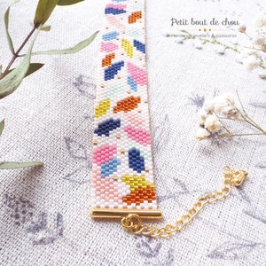 May include: A colorful beaded bracelet with a geometric pattern. The bracelet has a gold clasp and is made with white, blue, pink, yellow, and orange beads.