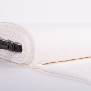 May include: A roll of white fabric with a black handle. The fabric is tightly rolled and appears to be a soft, textured material. The roll is positioned horizontally against a white background.