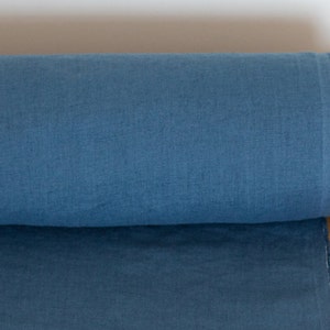 May include: A roll of blue linen fabric. The fabric has a slightly textured surface and is rolled up tightly.