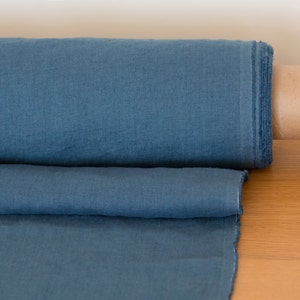 May include: A roll of blue linen fabric, unfurled and folded, with a brown cardboard core.