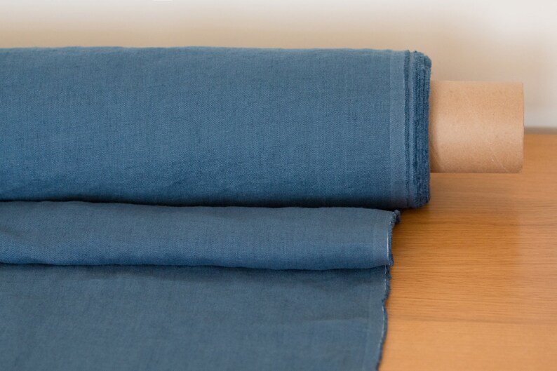 May include: A roll of blue linen fabric, unfurled and folded, with a brown cardboard core.