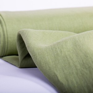 May include: A roll of light green fabric with a textured surface. The fabric is folded and rolled up, and the end of the roll is visible.