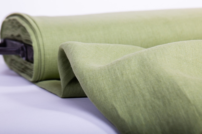 May include: A roll of light green fabric with a textured surface. The fabric is folded and rolled up, and the end of the roll is visible.