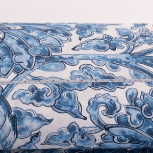 May include: A roll of fabric with a blue and white floral design. The pattern features stylized flowers and cloud motifs. A measuring tape indicates the fabric's width. The fabric is ideal for sewing and craft projects. The width is approximately 30 cm.