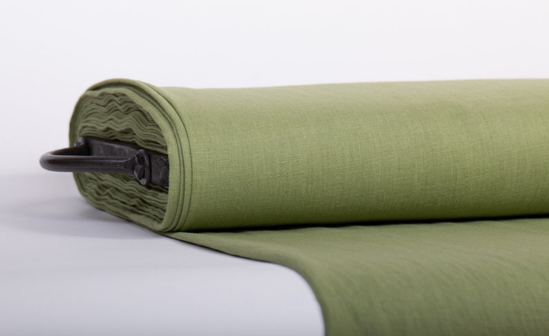 May include: A roll of green linen fabric, folded and displayed on a white surface. The fabric is smooth and has a subtle texture.