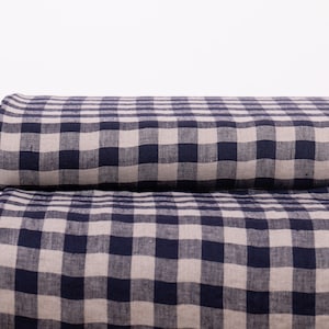 Può includere: Un rotolo di tessuto gingham blu e bianco. Il tessuto è tessuto con un motivo a quadri.