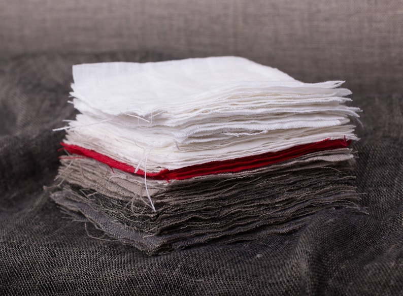 May include: A stack of fabric squares in various shades of gray, white, and red. The fabric is folded neatly and has a slightly textured surface.