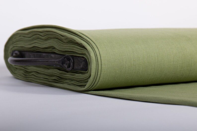 May include: A roll of olive green fabric with a black metal handle. The fabric is folded and rolled up, and the handle is attached to the roll.