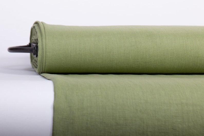May include: A roll of light green linen fabric. The fabric is rolled up and secured with a metal band.