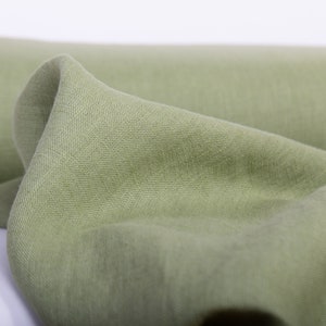 May include: A roll of soft, light green fabric. The fabric is folded and has a smooth texture.
