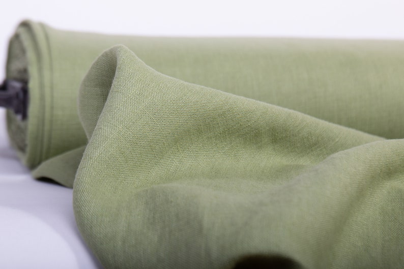 May include: A roll of soft, light green fabric. The fabric is folded and has a smooth texture.