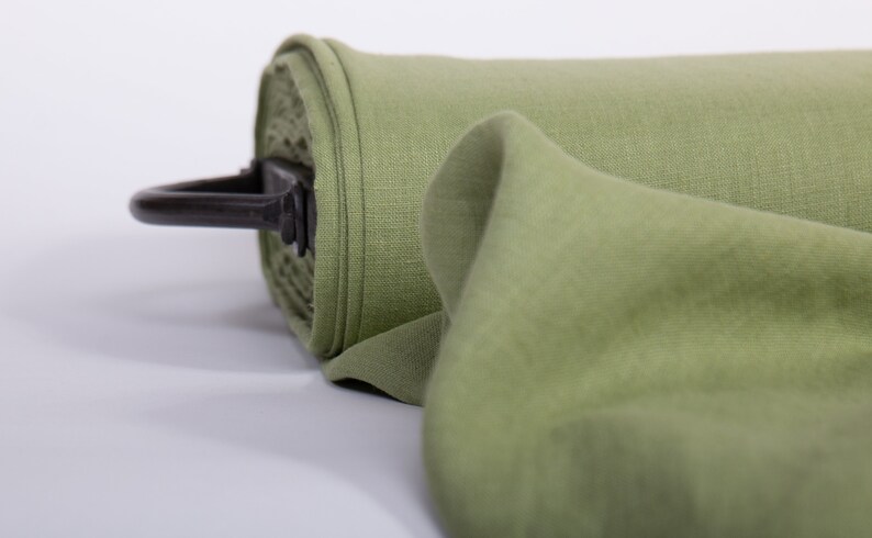 May include: A roll of green fabric with a black metal handle. The fabric is folded and has a soft, textured surface.