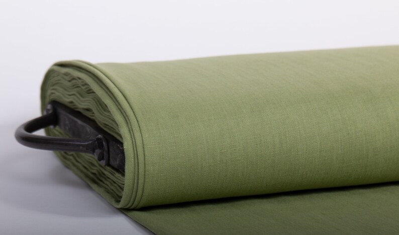 May include: A roll of green linen fabric, tightly wound and secured with a metal handle.