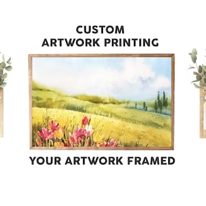 May include: A framed watercolour painting of a field of wildflowers with a blue sky and white clouds in the background. The text "CUSTOM ARTWORK PRINTING" and "YOUR ARTWORK FRAMED" is displayed above and below the painting.