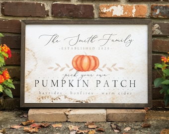 May include: A rectangular wooden sign with a dark brown frame. The sign reads "The Smith Family - Established 2020" above a watercolor pumpkin and the words "pick your own PUMPKIN PATCH". The sign is propped up on bricks.