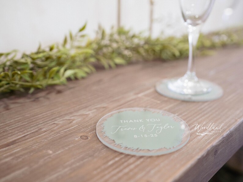 May include: A light green round coaster with the text "Thank You Jess & Tyler 8-15-23" in white lettering.