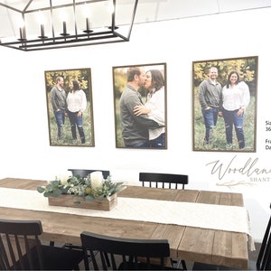 Puede incluir: Tres fotograf&iacute;as enmarcadas de una pareja en un ambiente de comedor. Las fotos miden 91,44 cm por 60,96 cm y tienen marcos de color marr&oacute;n oscuro. La mesa de comedor es de madera y tiene un camino de mesa blanco. Hay sillas negras alrededor de la mesa y una caja de madera con vegetaci&oacute;n y velas en el centro.