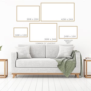 May include: A white loveseat with a green throw blanket, two end tables, and five framed pictures on the wall. The pictures are in different sizes and are labelled with their dimensions in inches. The text "COMMON 72" LOVESEAT" and "WOODLAND SHANTY" is also visible on the wall.
