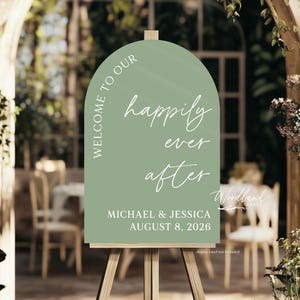 Puede incluir: Un cartel de bienvenida de boda de color verde en forma de arco con texto blanco que dice "Bienvenido a nuestro felices para siempre Michael & Jessica 8 de agosto de 2026".
