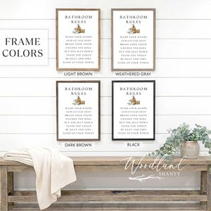 May include: Four framed bathroom rule signs in light brown, weathered gray, dark brown, and black. Each sign has the text "Bathroom Rules" and a list of rules. A wooden bench with a folded blanket and a plant are in the foreground.