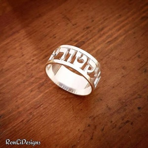 May include: A silver ring with the Hebrew word "שלום" (Shalom) cut out of the band.