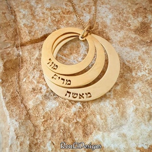 May include: Gold necklace with three interlocking circles, each inscribed with a Hebrew word. The words are "Ma'asha", "Moed", and "Chai".