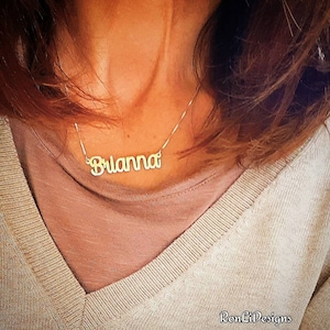 May include: A gold necklace with the name "Brianna" spelled out in cursive.