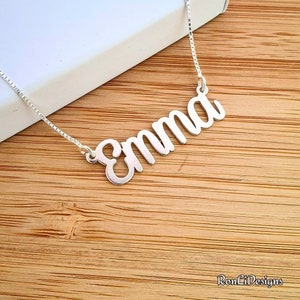 May include: A silver necklace with the name "Emma" spelled out in cursive script.