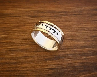 May include: A silver and gold ring with Hebrew writing engraved on the band.